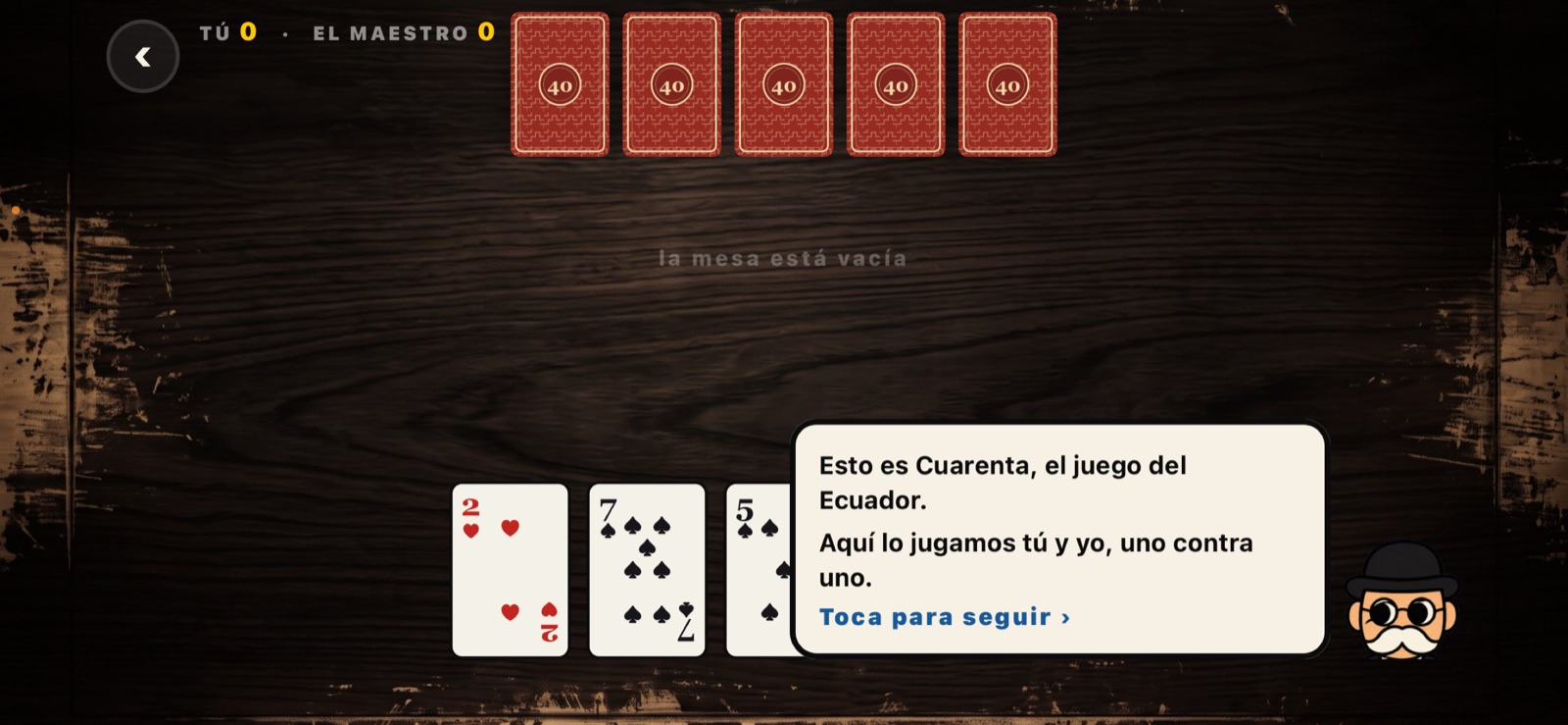 El Maestro explicando la primera mano sobre la mesa de madera.